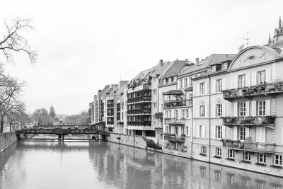 Bridge over river amidst buildings in city against sky