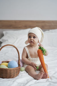 Cute girl with carrot sitting on bed