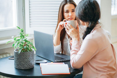 Businesswomen with laptop planning at desk in cafeteria