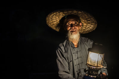 Portrait of man wearing hat against black background