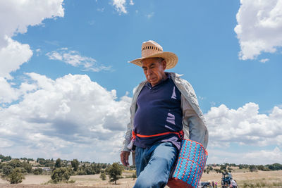 Mature male farmer with hat walking in field