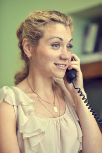 Smiling woman talking on telephone at home