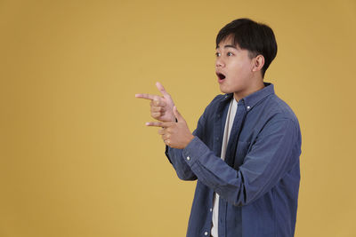 Side view of boy looking away against orange background