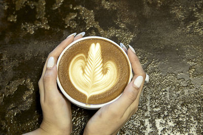 Directly above shot of hand holding coffee cup