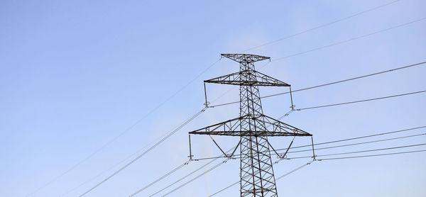 Low angle view of electricity pylon against clear sky