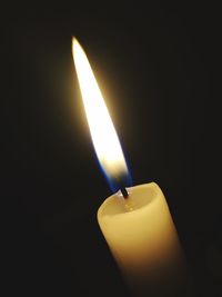 Close-up of lit candle against black background