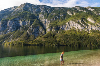 Woman walking in lake against mountains