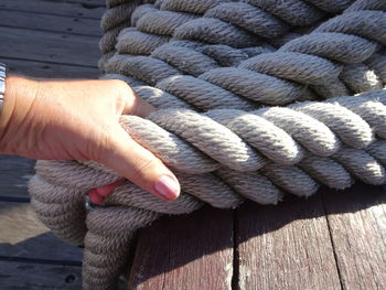 High angle view of cropped hand holding rope over table