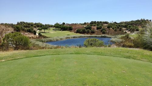 Scenic view of golf course against clear blue sky