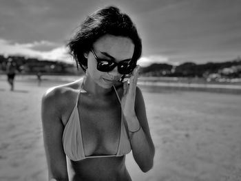 Portrait of young woman wearing sunglasses standing at beach
