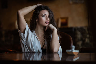 Portrait of beautiful young woman sitting on table