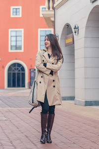 Portrait of young woman standing against wall