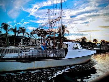 Fishing boats moored at harbor against sky