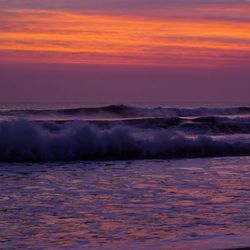 Scenic view of sea against dramatic sky during sunset