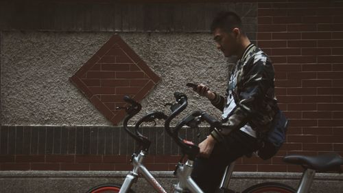 Side view of young man cycling on bicycle in city