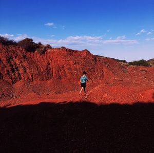 Rear view of man on rock against sky