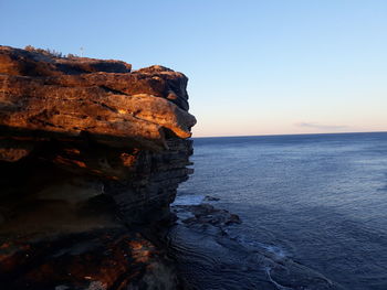 Rock formations in sea against clear sky