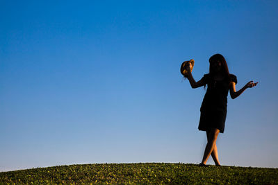 Full length of woman posing on field against clear sky