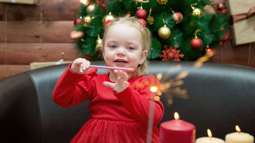 Portrait of cute girl blowing bubbles while sitting at home