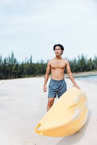 Portrait of shirtless man sitting on beach