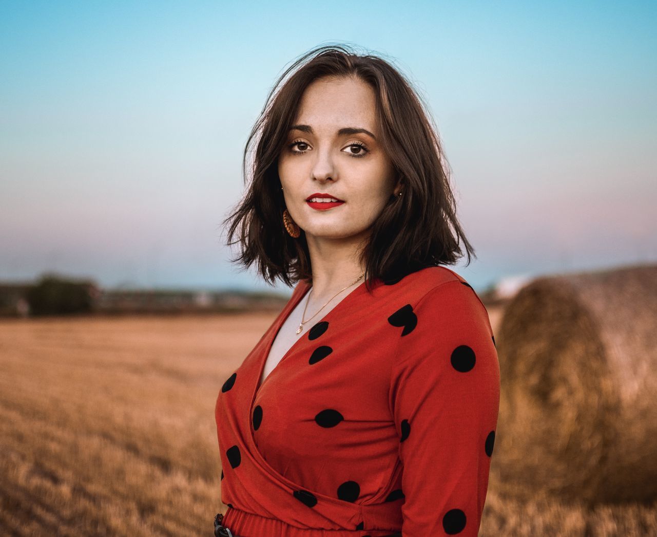 PORTRAIT OF BEAUTIFUL YOUNG WOMAN STANDING ON FIELD AGAINST SKY