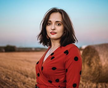 Portrait of woman standing on field against sky