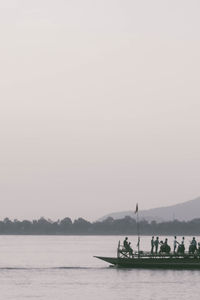 People on boat sailing in river against clear sky