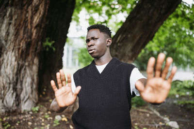 Shocked young 20s african man doing no stop sign with palms of hands