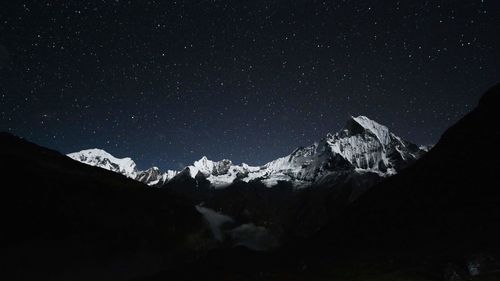 Scenic view of snowcapped mountains against sky at night