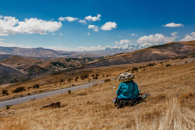 Rear view of man on field against mountain range