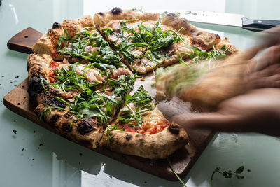 Close-up of hand holding pizza in plate on table