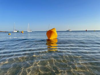 Sailboats in sea against clear sky