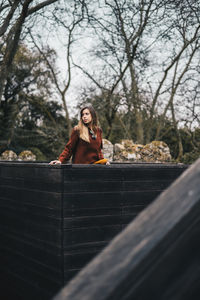 Young woman looking at view while standing on top of tower against sky