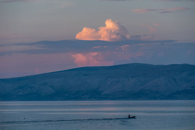 Person surfing in sea against sky during sunset