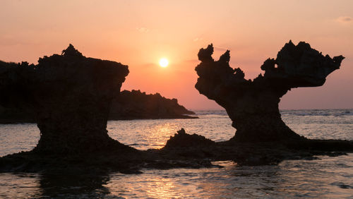 Silhouette rock formation on beach against sky during sunset in okinawa, japan