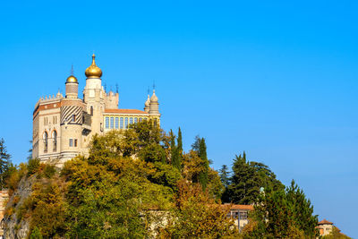 View of trees and building against blue sky