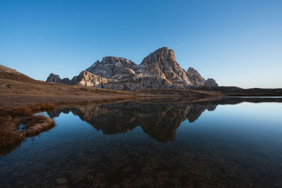 Scenic view of lake and mountains against clear blue sky