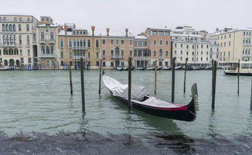 Gondola moored at canal against buildings in city