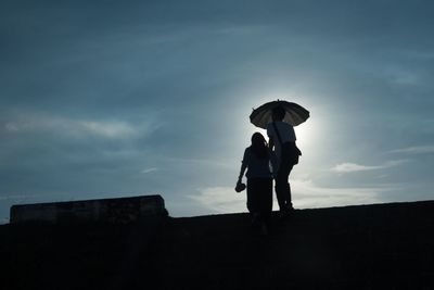 Low angle view of silhouette woman standing against sky