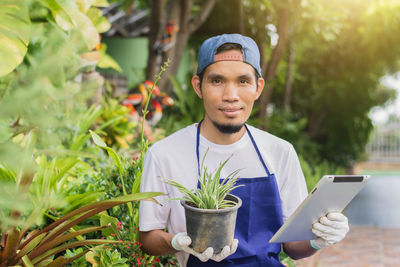 Portrait of young man holding smart phone while standing outdoors