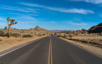 Road leading towards mountains against sky