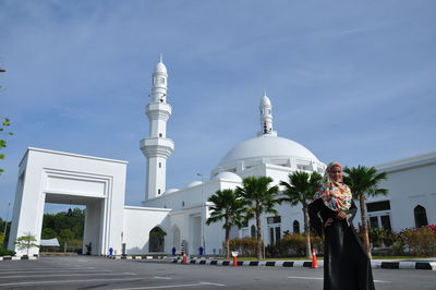Teenage girl wearing traditional clothing standing against mosque during sunny day