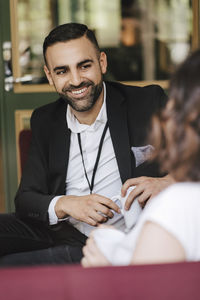 Smiling male professional looking at female colleague while discussing during networking event