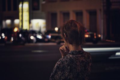 Rear view of man standing on street at night