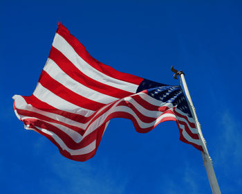 Low angle view of flag against clear blue sky