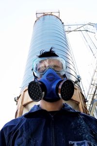 Low angle portrait of man standing outside factory