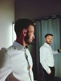 Handsome man looking at reflection on mirror at home