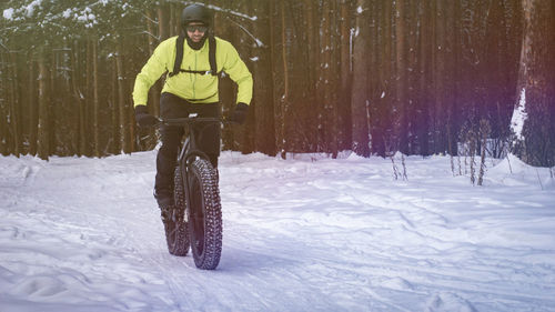 Man riding bicycle on snow covered field
