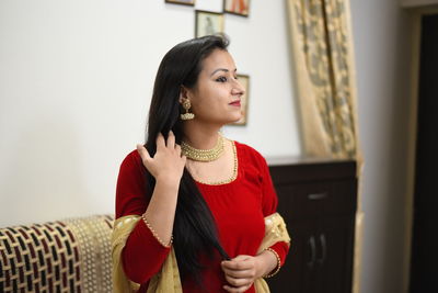 Smiling woman in traditional clothing standing at home