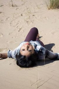 Portrait of young woman lying on sand